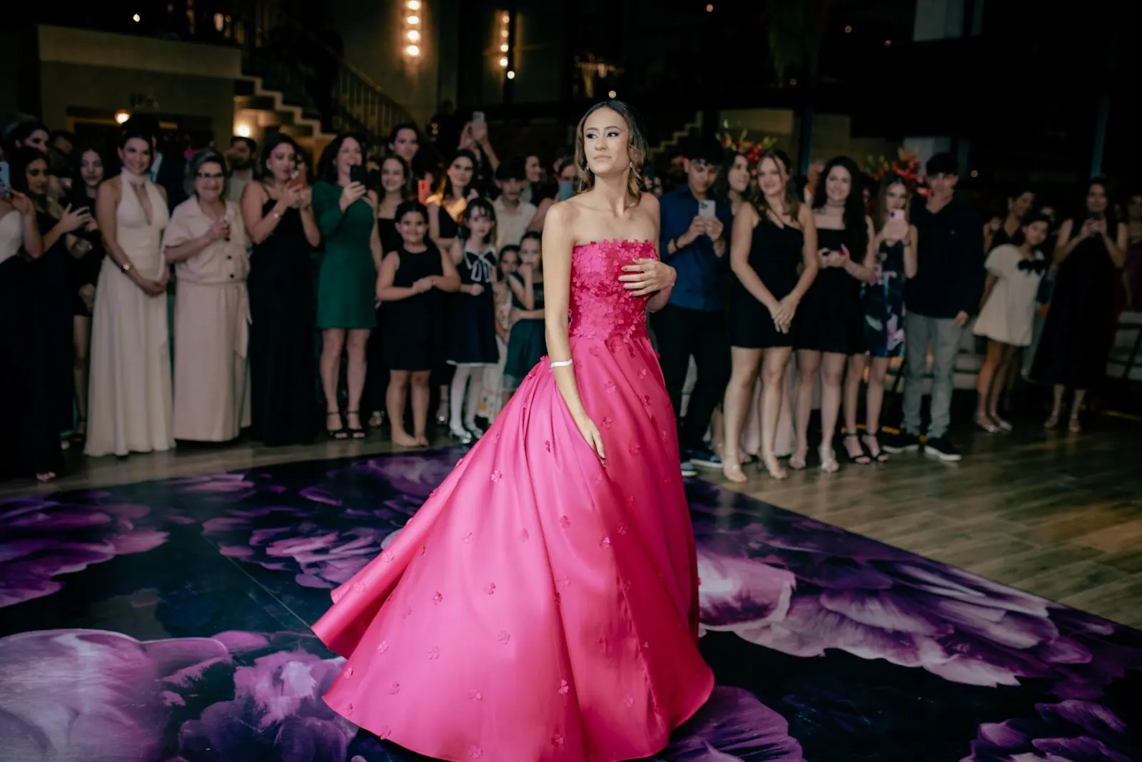 Debutante com vestido rosa longo durante apresentação na pista da festa de 15 anos no Espaço Coral em Batatais SP, com convidados ao redor